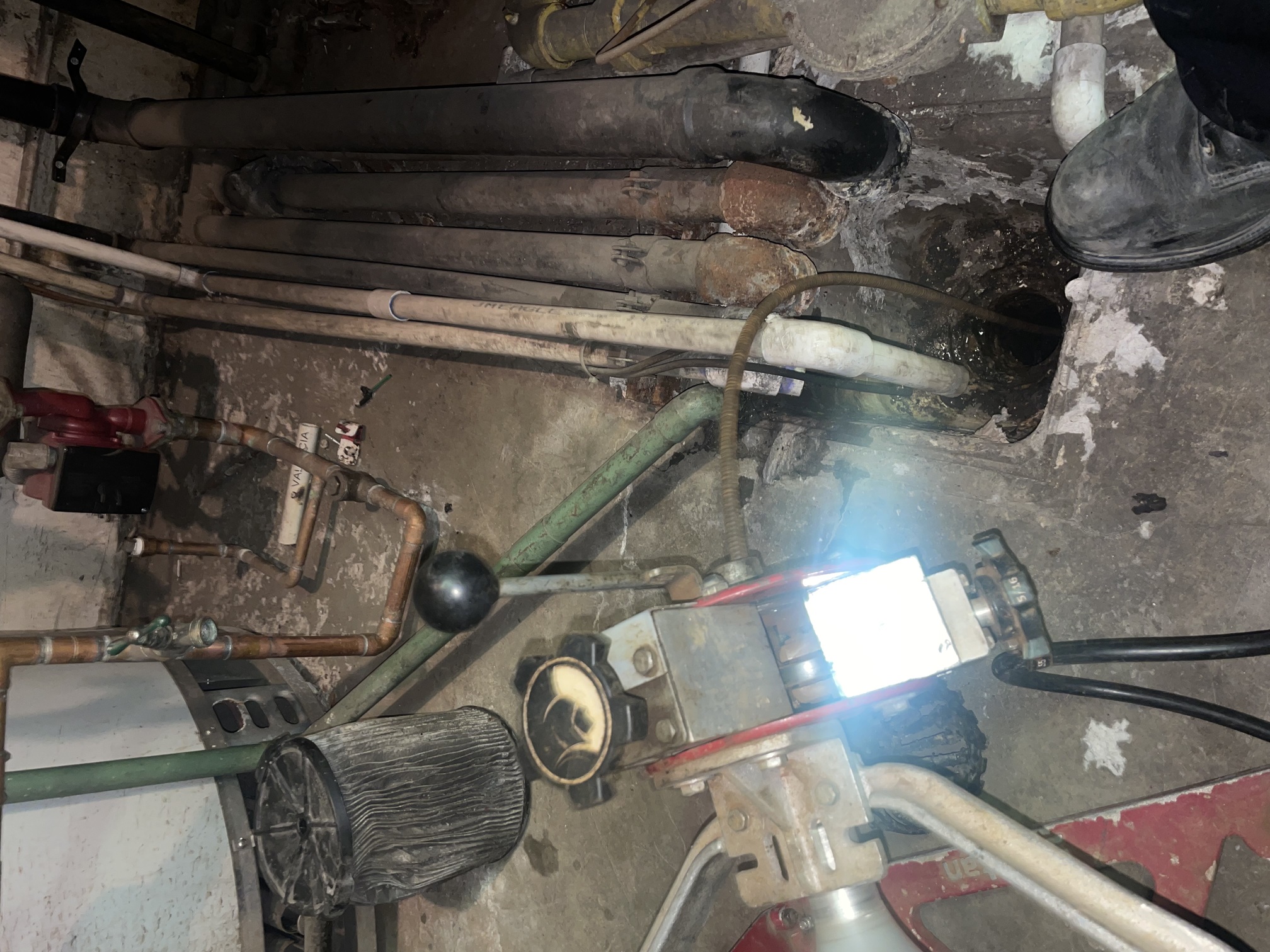 Plumber performing emergency repair in confined commercial mechanical room