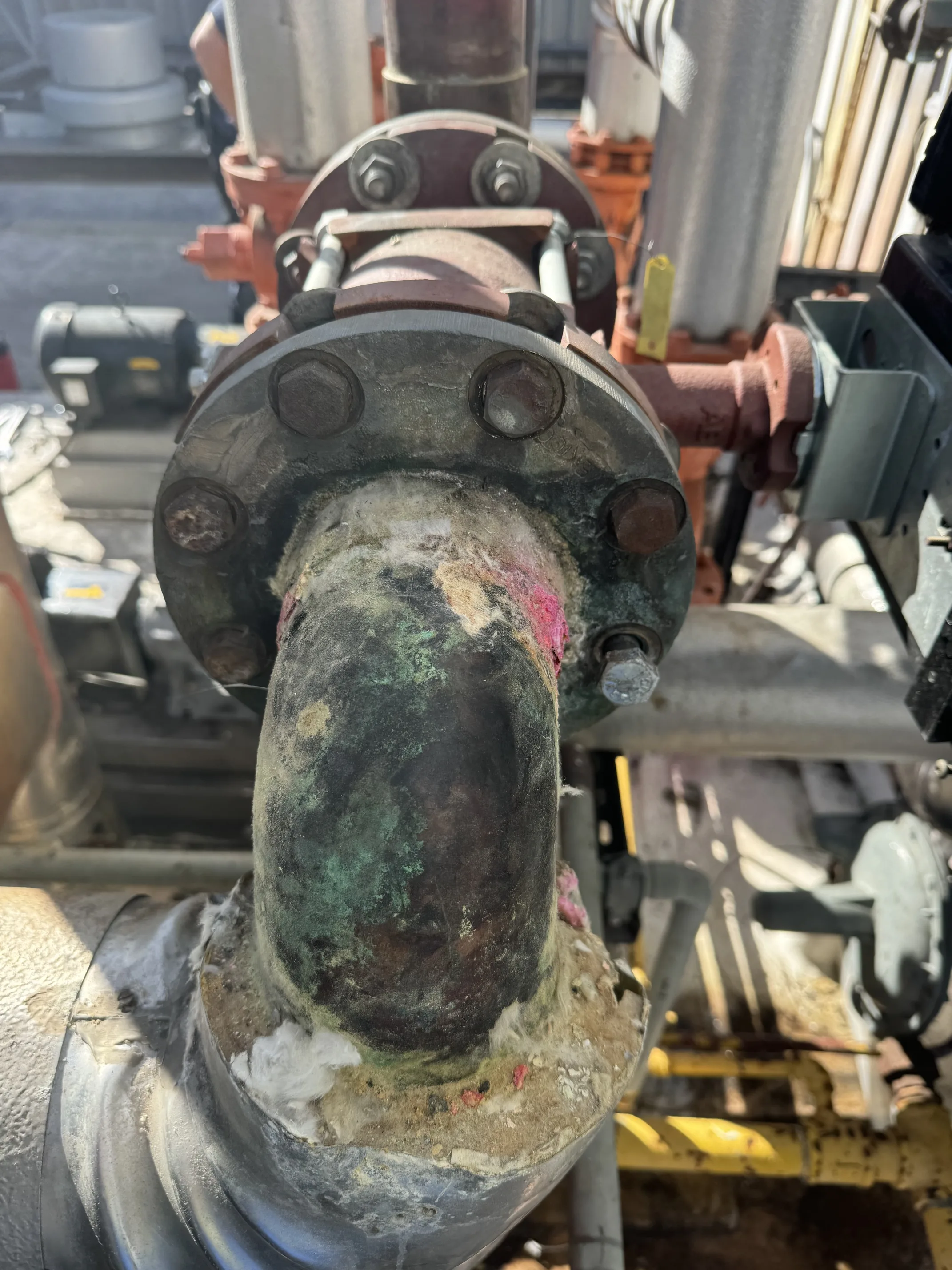 Corroded industrial pipe flange requiring commercial plumbing repair at logistics facility