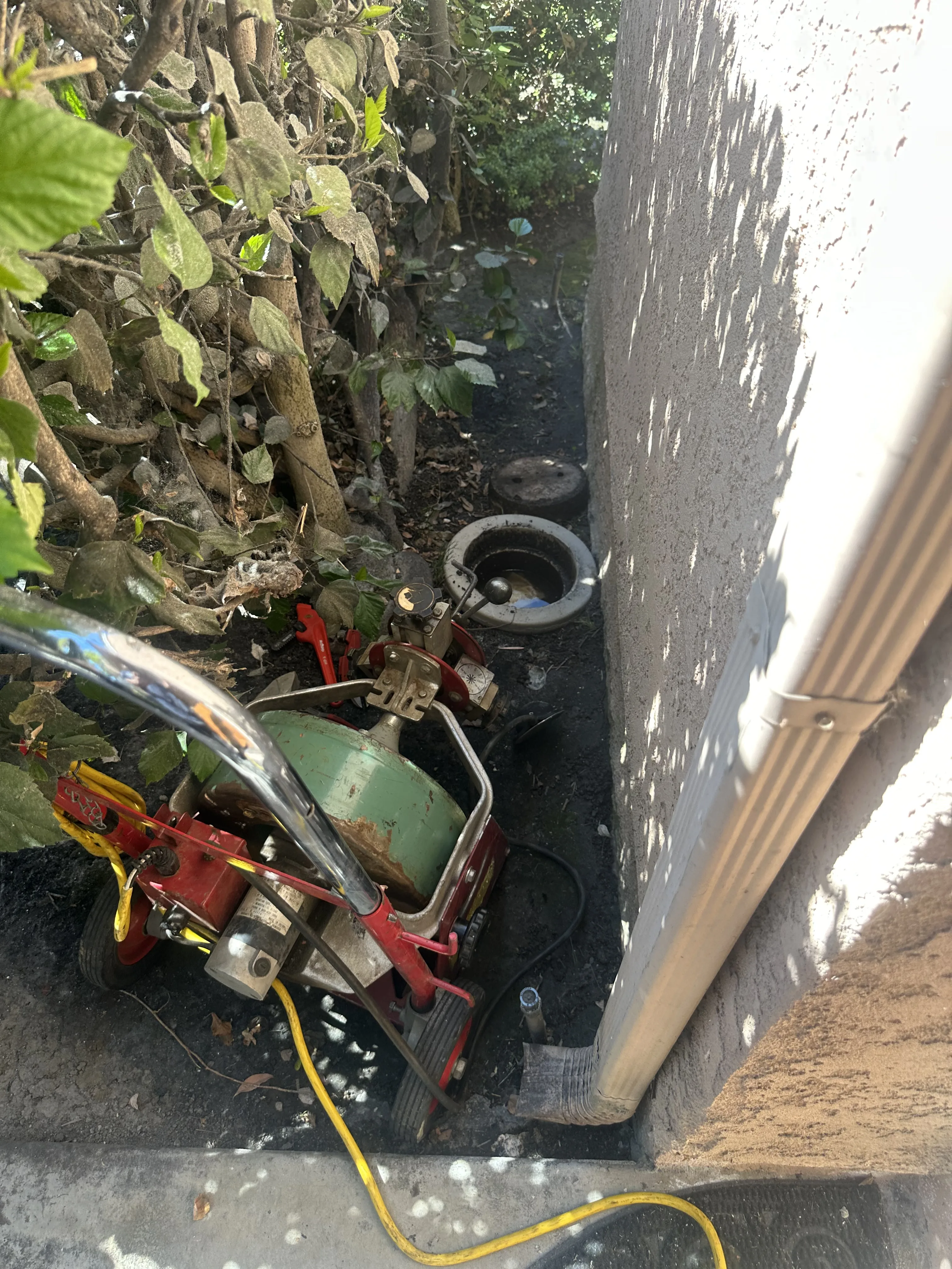Commercial drain cleaning machine positioned at outdoor cleanout access point